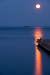 A detail of a industrial pier with full blood moon in the background.