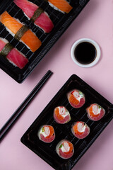 nigeri and rolls, salmon, tuna, soy, chopsticks. pink background, flat lay.
