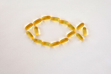 fish from gold capsules omega 3 on a white background