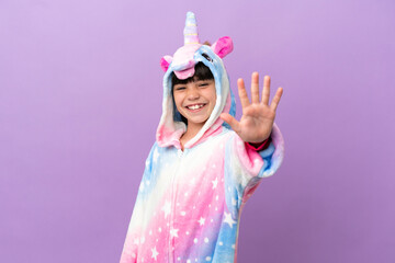 Little kid wearing a unicorn pajama isolated on purple background counting five with fingers