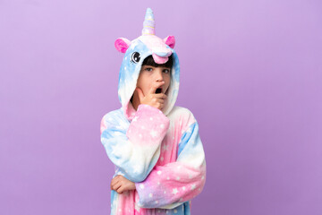 Obraz na płótnie Canvas Little kid wearing a unicorn pajama isolated on purple background surprised and shocked while looking right