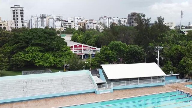 dron mostrando el pabell&oacute;n ol&iacute;mpico de nataci&oacute;n desde arriba, p&aacute;jaro cruzando delante de la c&aacute;mara, fondo de la ciudad de santo domingo rep&uacute;blica dominicana