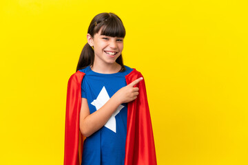 Little super hero kid isolated on purple background pointing to the side to present a product