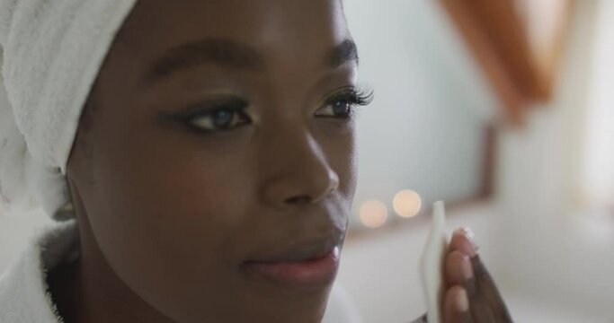 Portrait of african american attractive woman removing make up in bathroom