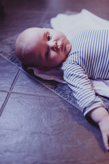 baby lies on a rug in the bathroom on a warm floor