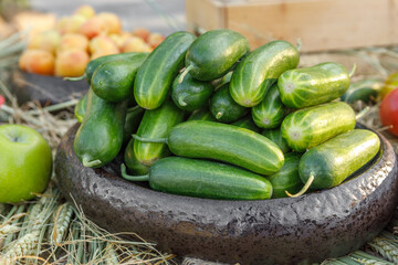 Ripe juicy cucumbers lie in a wooden bowl, arranged with straw.