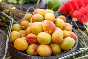 Ripe juicy sweet apricots lie in a wooden bowl, arranged with straw.