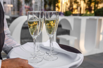 A man is holding crystal glasses of champagne in his hands.