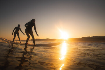 2 female surfers catch a wave at sunrise