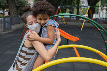 Fototapeta na wymiar Mother and daughter hugging at playground outside in pandemic life