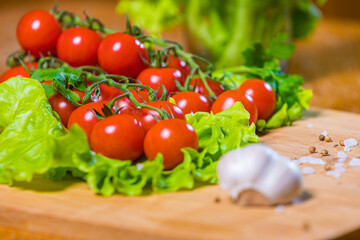 Fresh cherry tomatoes with green salad and garlic on a cutting board. Healthy food concept. Vegetarianism.