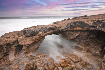 Arch shaped rock formation in the coastline at the sunset.
