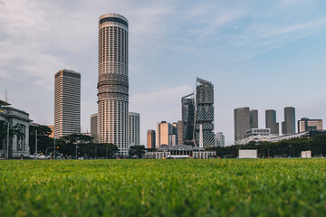 Obraz premium Padang playing green fields with a low angle of the city convention center and other skyscrapers, Singapore.