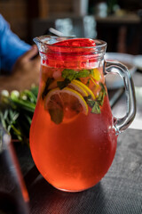 Lunch with a decanter of chilled red fruit drink with lemon and mint wedges. Close-up.