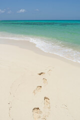 Fototapeta na wymiar A deserted tropical beach with human footprints on the sand