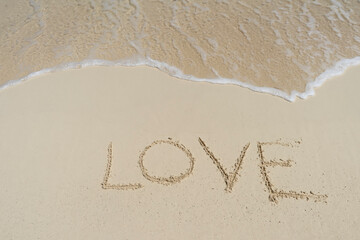 The text LOVE on the sand of a tropical beach