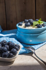 Morning fresh breakfast made from natural products from cottage cheese and blueberries. Nutritious cottage cheese and berries contain healthy vitamins. Blue background.
