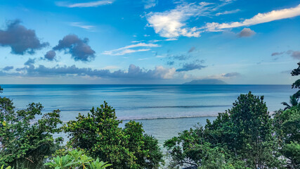 Fototapeta na wymiar Cloudy blue sky, calm blue Indian Ocean, Seychelles, Mahe, Beau Vallon