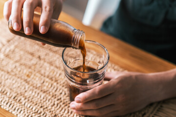 Pouring icy cold brew coffee from the bottle into the glass