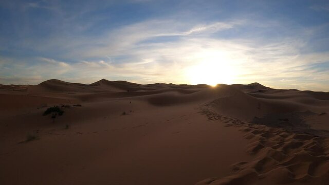 The sun just rises over the sand dunes in a desert untouched landscape