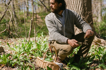 Man looking around woods while foraging for wild ramps