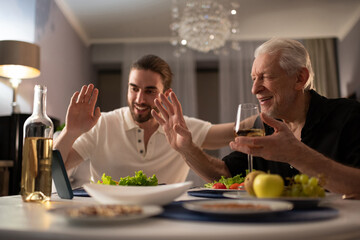 Grandfather and grandson greeting online relative during dinner