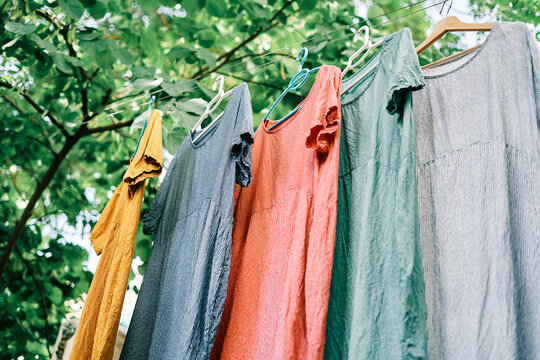 Colorful dresses hanging on hangers on the clothesline in the home garden