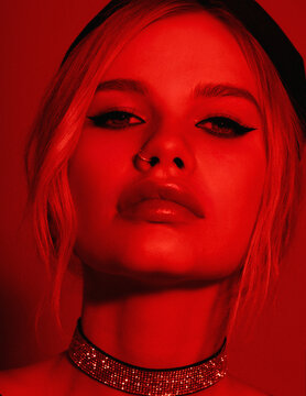 Beauty fashion portrait with red lighting filter. Beauty girl face close up. Closeup blonde woman with dark liner eyes and black hat. neon light red color. stylish fashion portrait art - imag