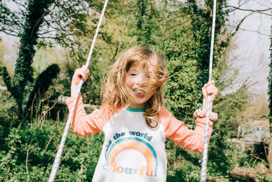 young girl happily swimming on a swing in a beautiful park in England