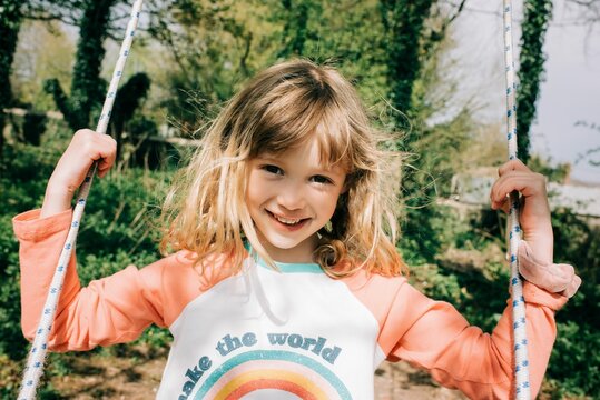 girl sat on a swing in a beautiful garden in the English countryside