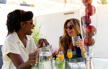 Multiracial girlfriends enjoying fresh drinks and talking