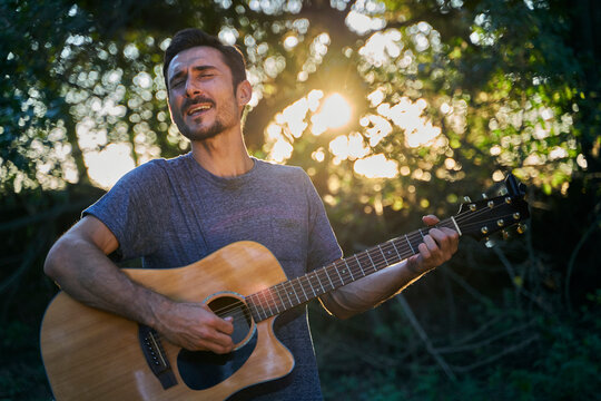 young man playing guitar at sunset