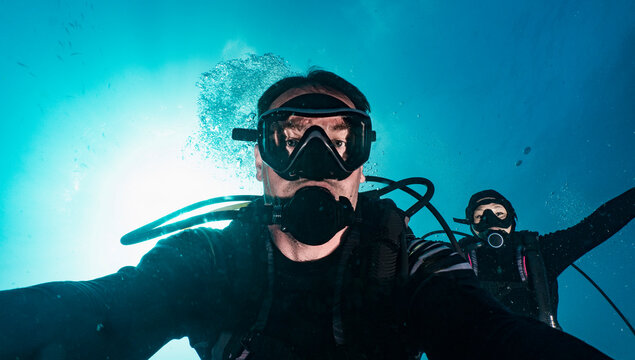 divers taking selfie while descending into the blue at Raja Ampat