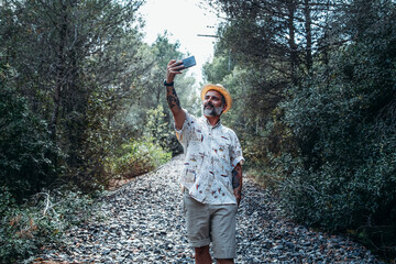 Bearded man making a selfie on the abandoned train track in the mountain