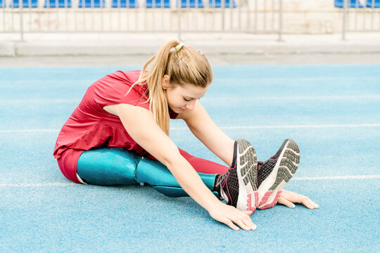 Sportswoman with prosthesis stretching legs