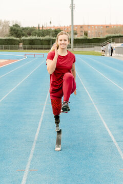 Cheerful female runner with prosthesis training at stadium