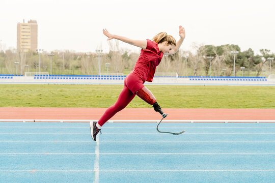 Sportswoman with prosthetic leg running on track