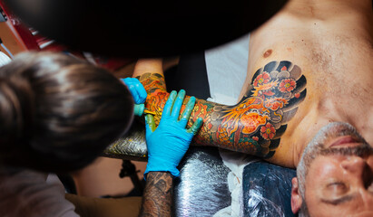 Aerial view of an tattoo artist working on a customer's arm.