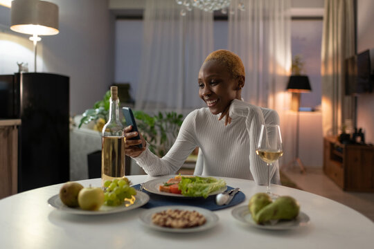 Young woman having dinner and making video call on smartphone - Powered by Adobe