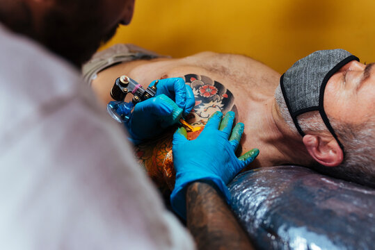 Close up of hands of an artist tattooing on a customer's arm.