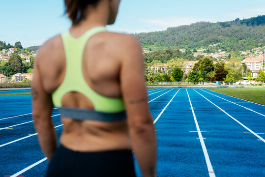 Anonymous young female sprinter standing on an athletics track