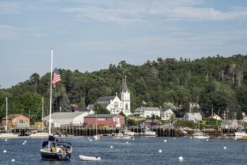 f Boothbay Harbor, Maine. Lobster and fishing boats moored in the harbor with church in background