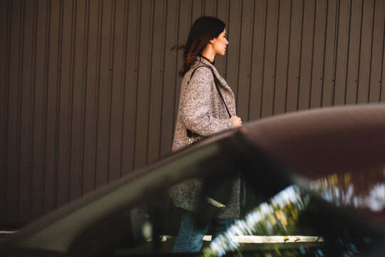 Woman walking against wall on street in city