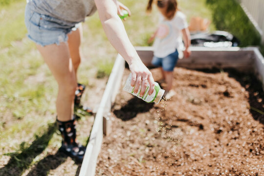 Mother and daughter prepare backyard garden bed for planting