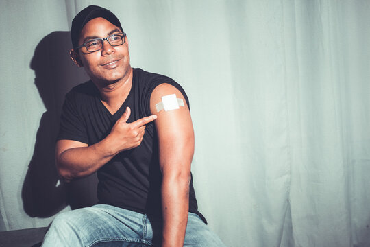 Latino brown man showing arm after covid vaccination