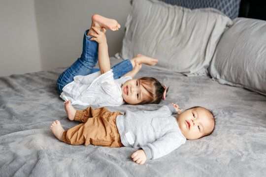 Asian Chinese girl and little newborn baby brother playing together.
