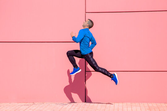 Sporty man exercising on fuchsia wall