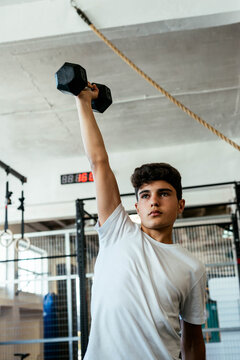 Young athlete lifting dumbbells in the middle of a workout