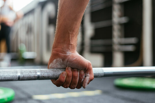 Anonymous sportsman holding a barbell in a crossfit box
