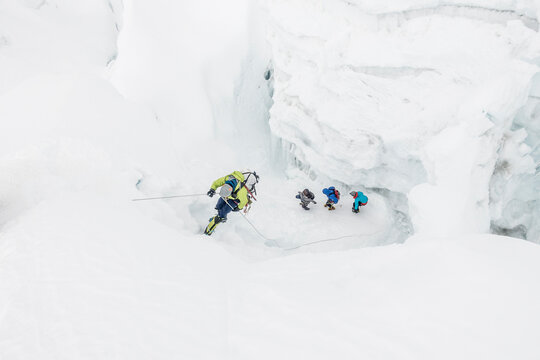 Climber on rappel while team navigates icefall
